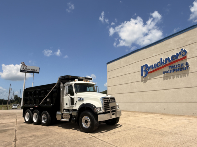 Mack GU713 dump truck on pavement in front of a Bruchner's Truck Equipment building.