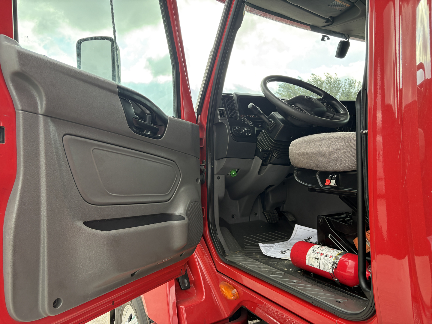 Truck cab interior showing steering wheel and driver's seat in a red 2022 International LT.