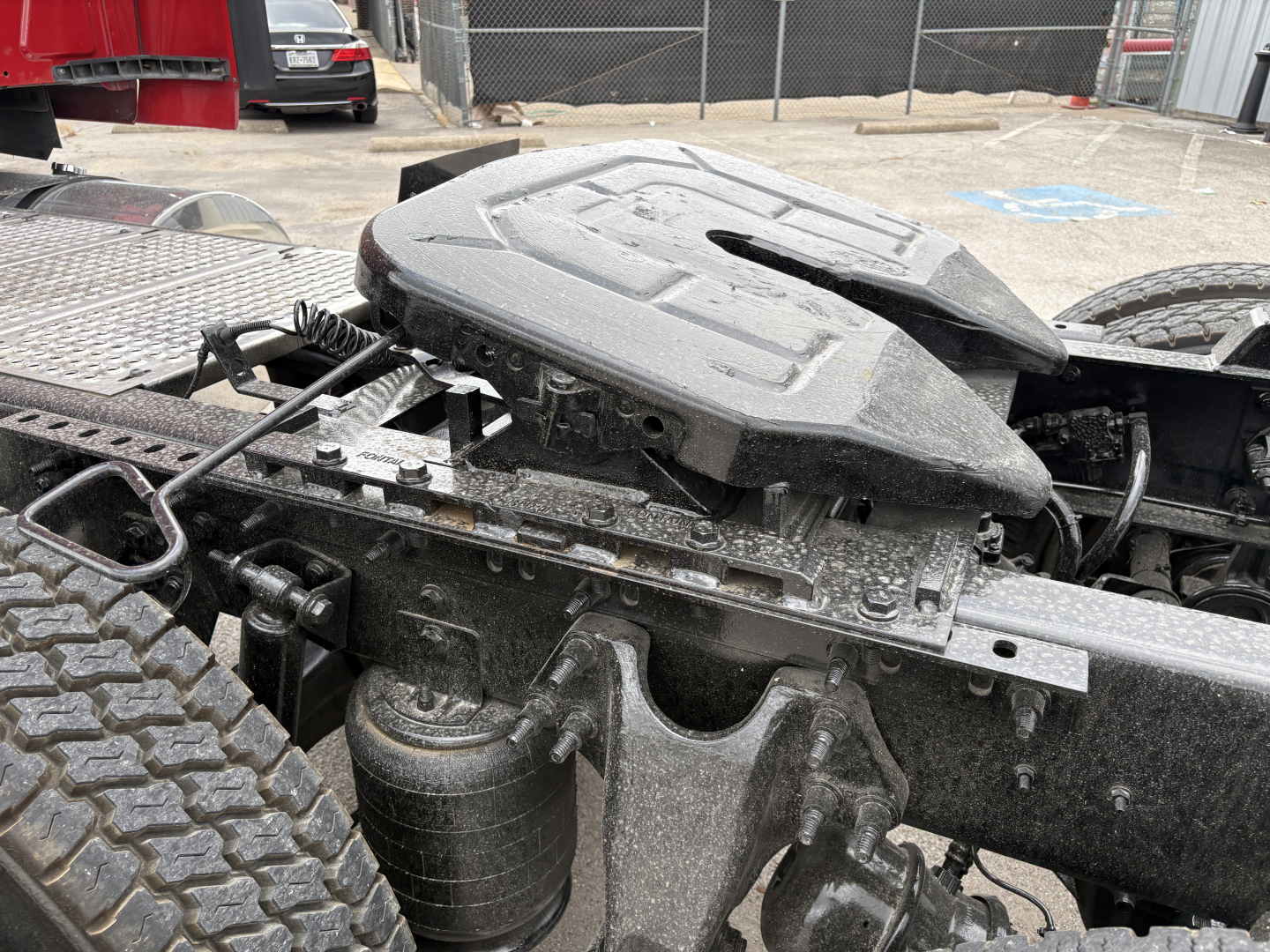 Tractor-trailer fifth wheel and coupling area with air reservoir and exposed frame; visible components include the hitch mounting and suspension near the rear wheels.