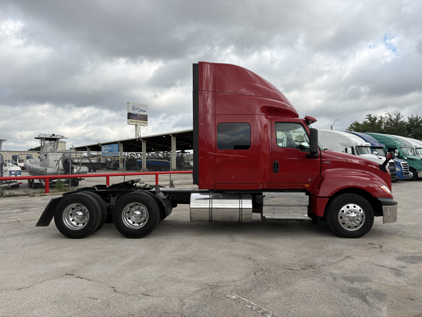 Truck side profile showing a red International LT tractor with sleeper cab and dual rear axles.