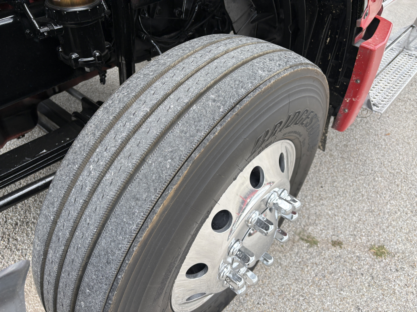 Truck wheel and tire close-up showing tread and chrome lug nuts, part of a 2022 International LT in-spec wheel assembly.