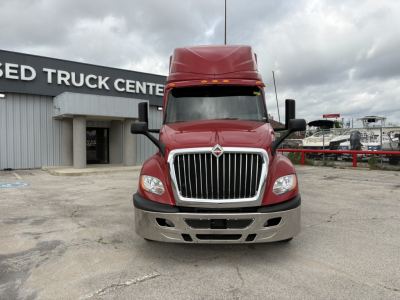 Truck front view of a red 2022 International LT in a used truck lot, showing chrome grille, bumper, hood, and headlights.