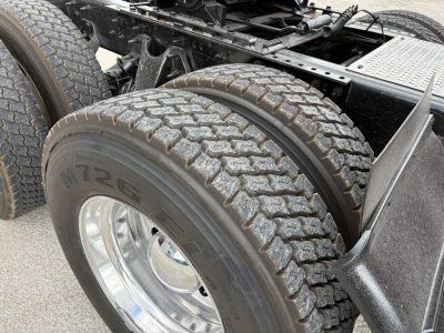 Dual rear tractor tires and chassis of a 2022 International LT truck showing tire treads and fuel/air lines, partial frame and steps.
