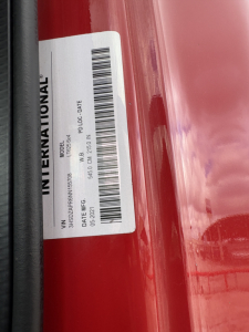 International truck label on door frame with barcode and VIN details visible; white sticker shows INTERNATIONAL text and barcodes.