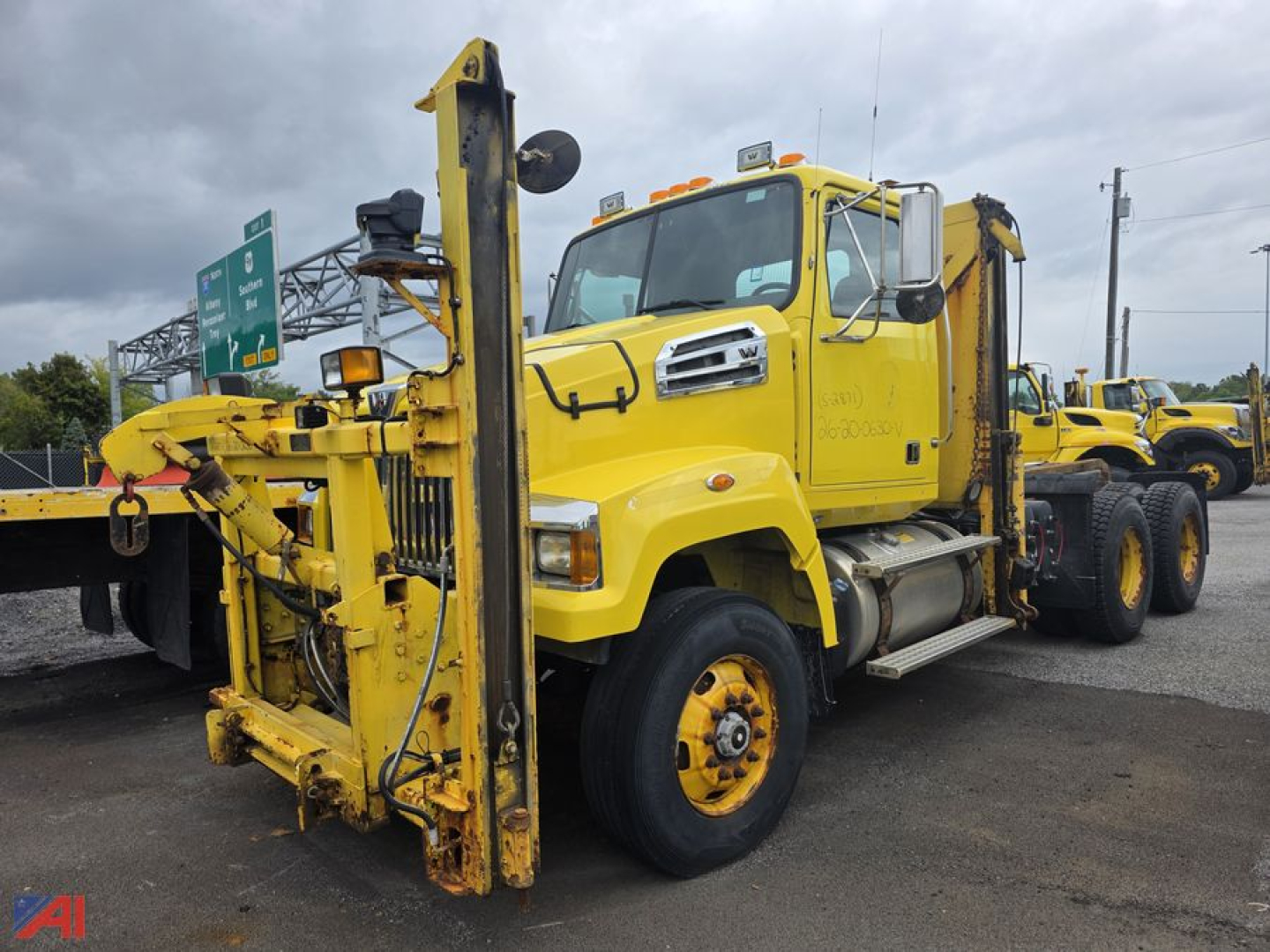 Yellow Western Star 4700 SF cab and chassis truck with mounted heavy-duty boom and winch, front view showcasing front axle, grille, and windshield.