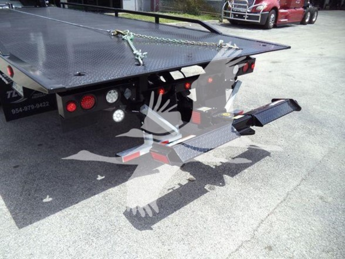 Truck rollback bed of a 2018 Peterbilt 337 showing rear platform and steps with hydraulic components and back lights.