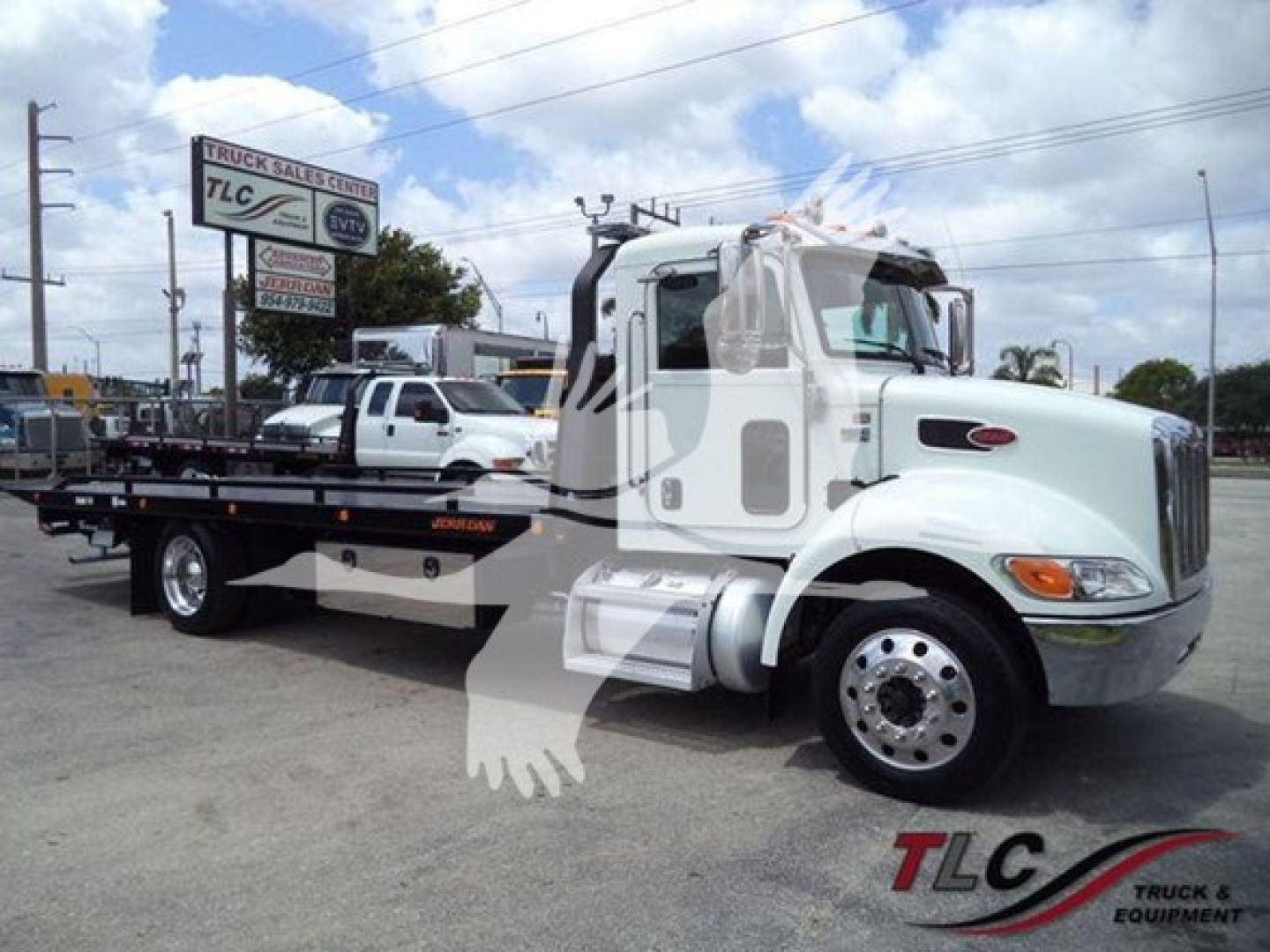 Truck image: 2018 Peterbilt 337 rollback tow truck in white with a flatbed, side mirrors and chrome wheels, VIN tag and stock number visible.