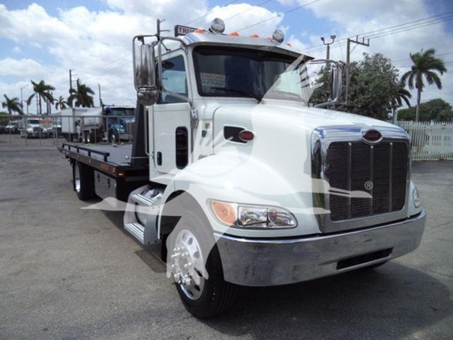 2018 Peterbilt 337 rollback truck with side flatbed, chrome grille, and dual mirrors. Front view shows Peterbilt emblem and headlights; truck is white with chrome bumper.