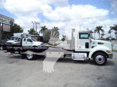 2018 Peterbilt 337 rollback truck side view showing white cab and long flatbed with hydraulic lines and wheel setup.