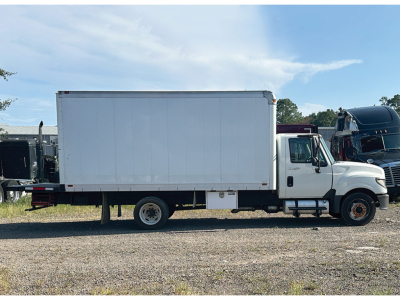 Truck side view of a 2012 International TerraStar box truck, white cargo box, cab with dual rear wheels, on gravel lot.