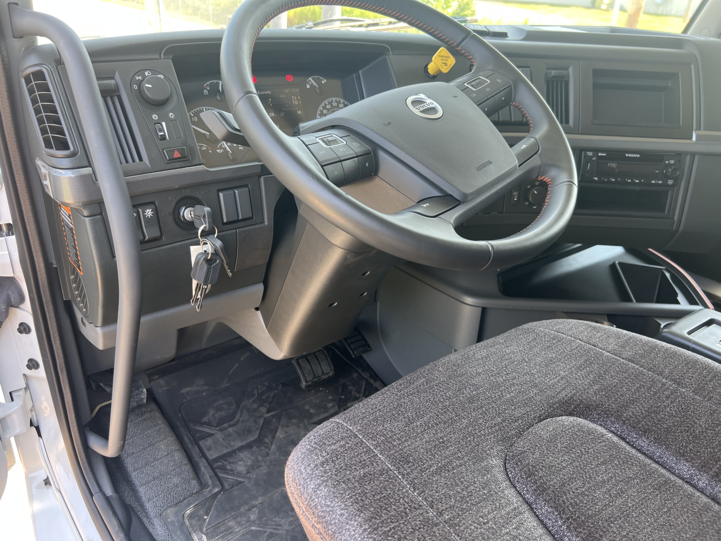 Volvo VHD64F300 truck cabin interior showing steering wheel, dashboard, ignition with key, pedals, and driver seat.