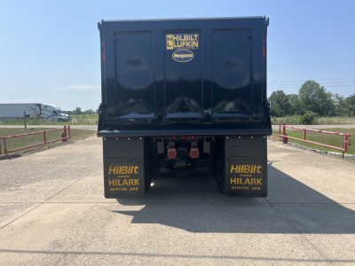 Rear view of a new Volvo VHD64F300 dump truck showing Hilbilt halrack mudflaps and bumper, with stock and VIN numbers not visible in this view.
