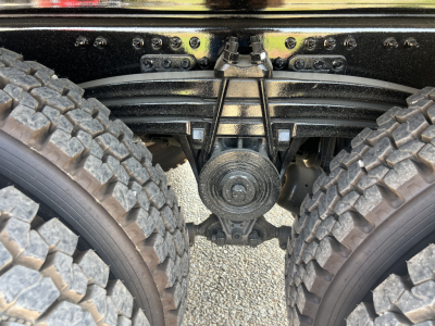 Rear view of Volvo VHD64F300 truck tandem axle suspension with leaf springs and differential housing visible between dual tires.