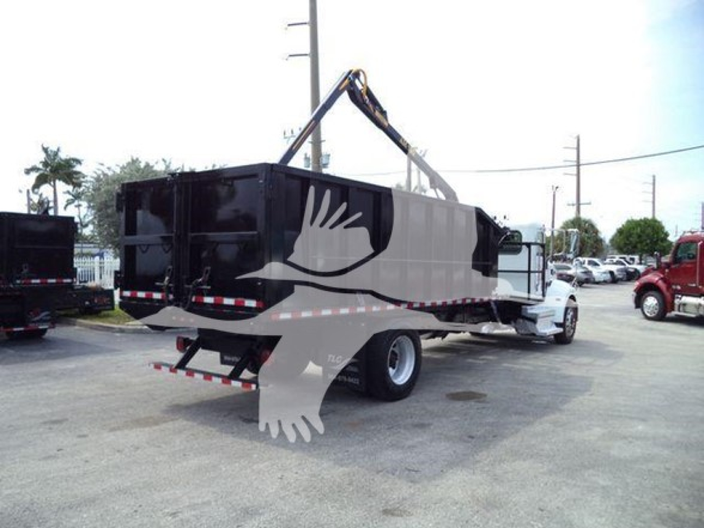 Peterbilt 337 dump truck with grapple attachment in driveway, side rear bunk, black container, white cab, crane arm overhead, stock number T18986.