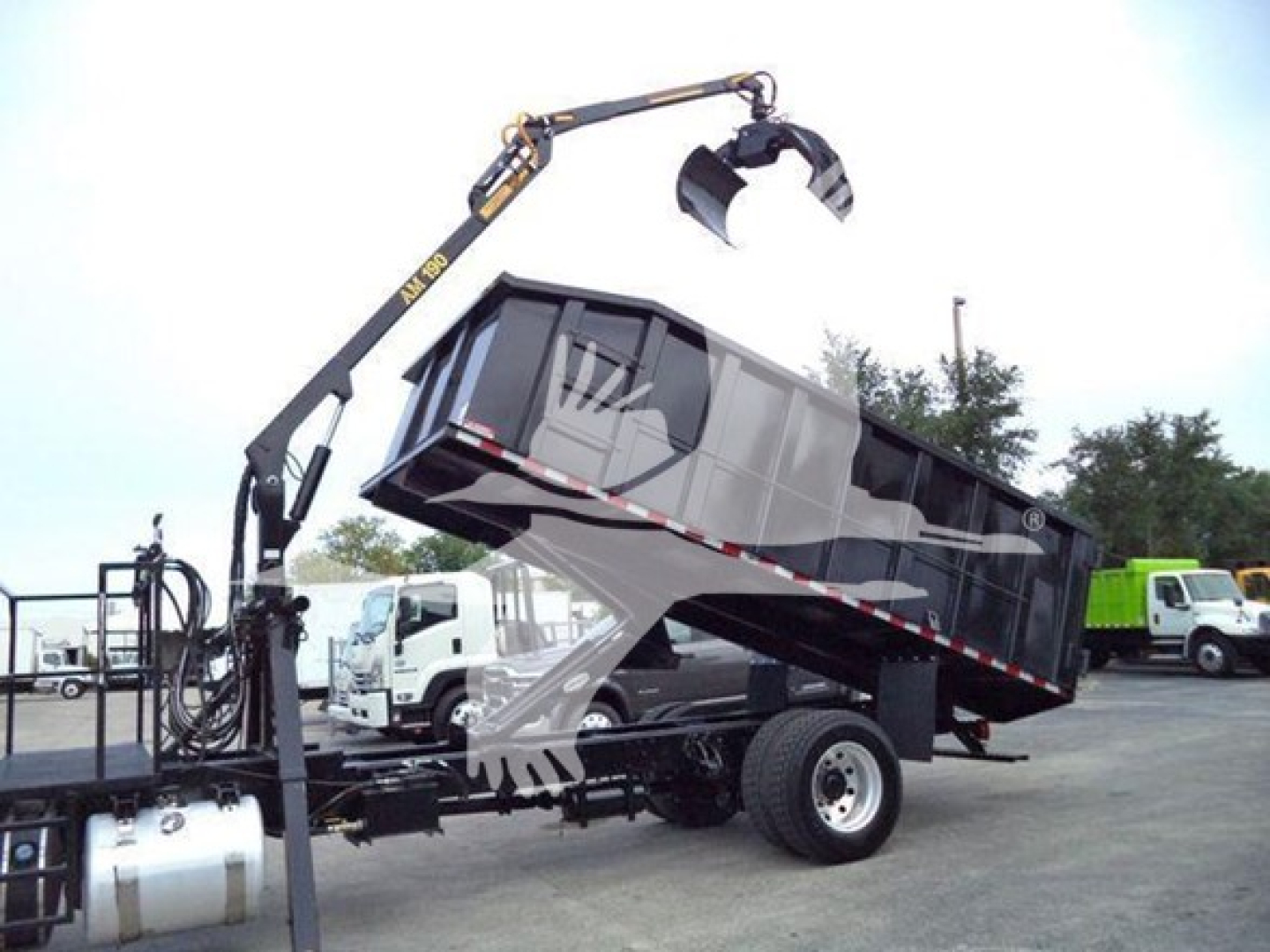 Truck with grapple attachment lifting a dump bed on a tilt trailer; hydraulic arm and claw visible; Peterbilt 337 context implied by listing.