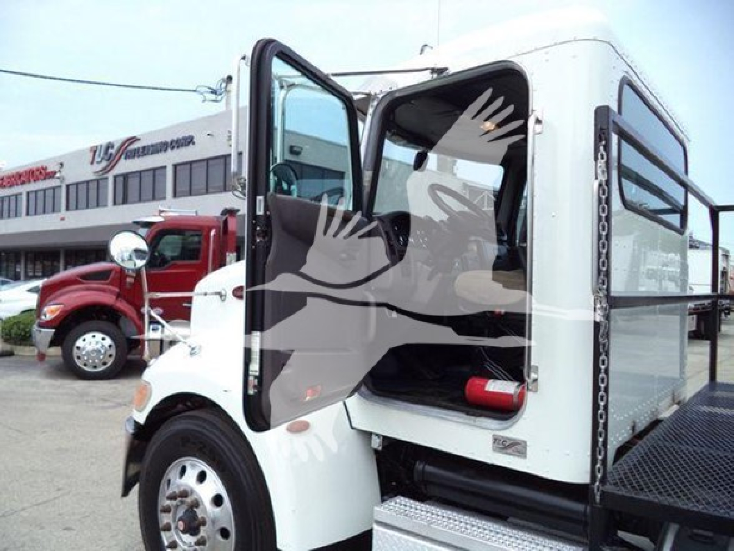Peterbilt 337 grapple truck cab with open door showing interior, white exterior, side step, and black chassis with metal platform.
