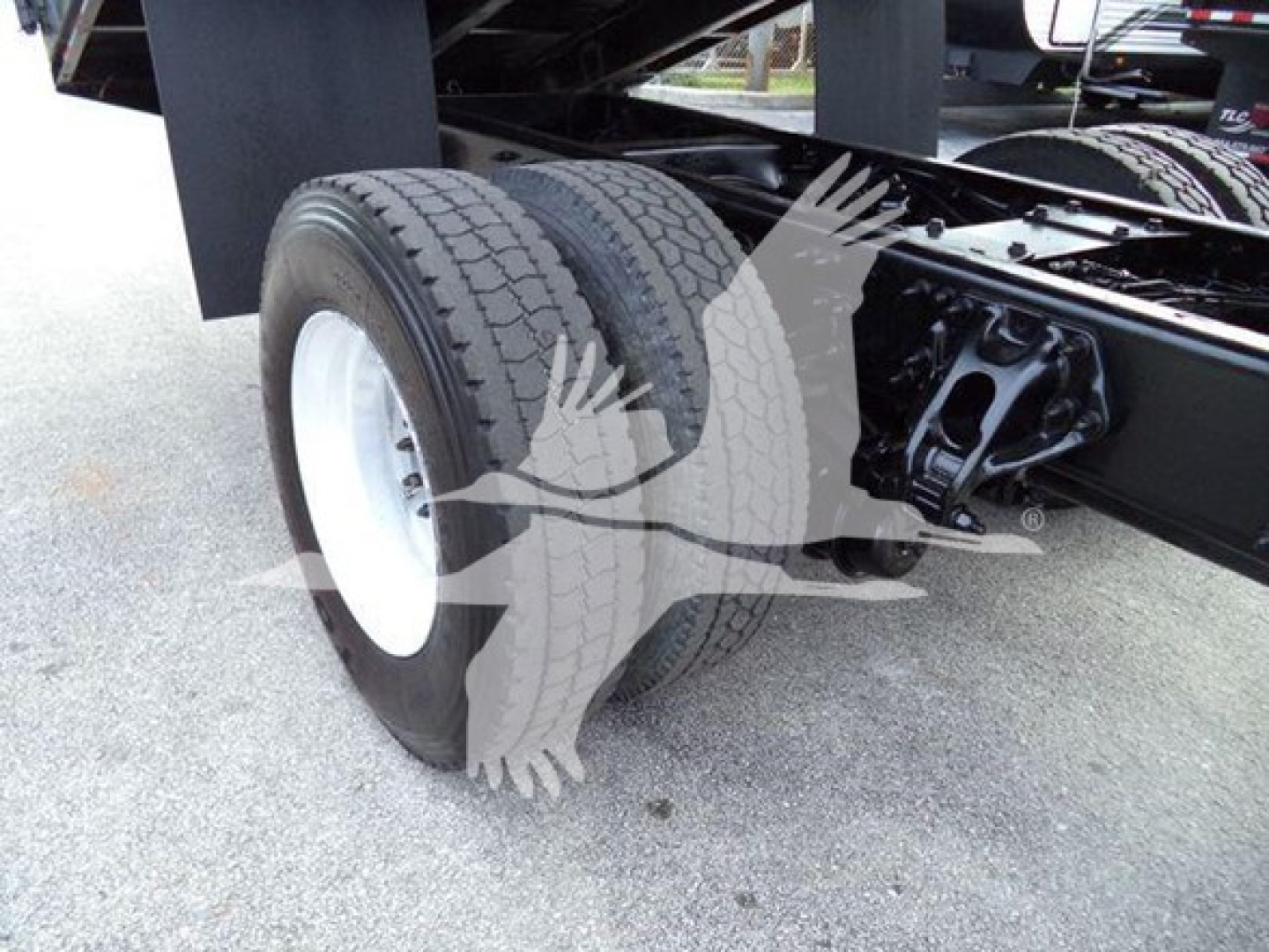 Peterbilt 337 chassis with dual rear tires and suspension, close-up of rear wheel area and axles showing two tires mounted on white rims under a grapple truck.