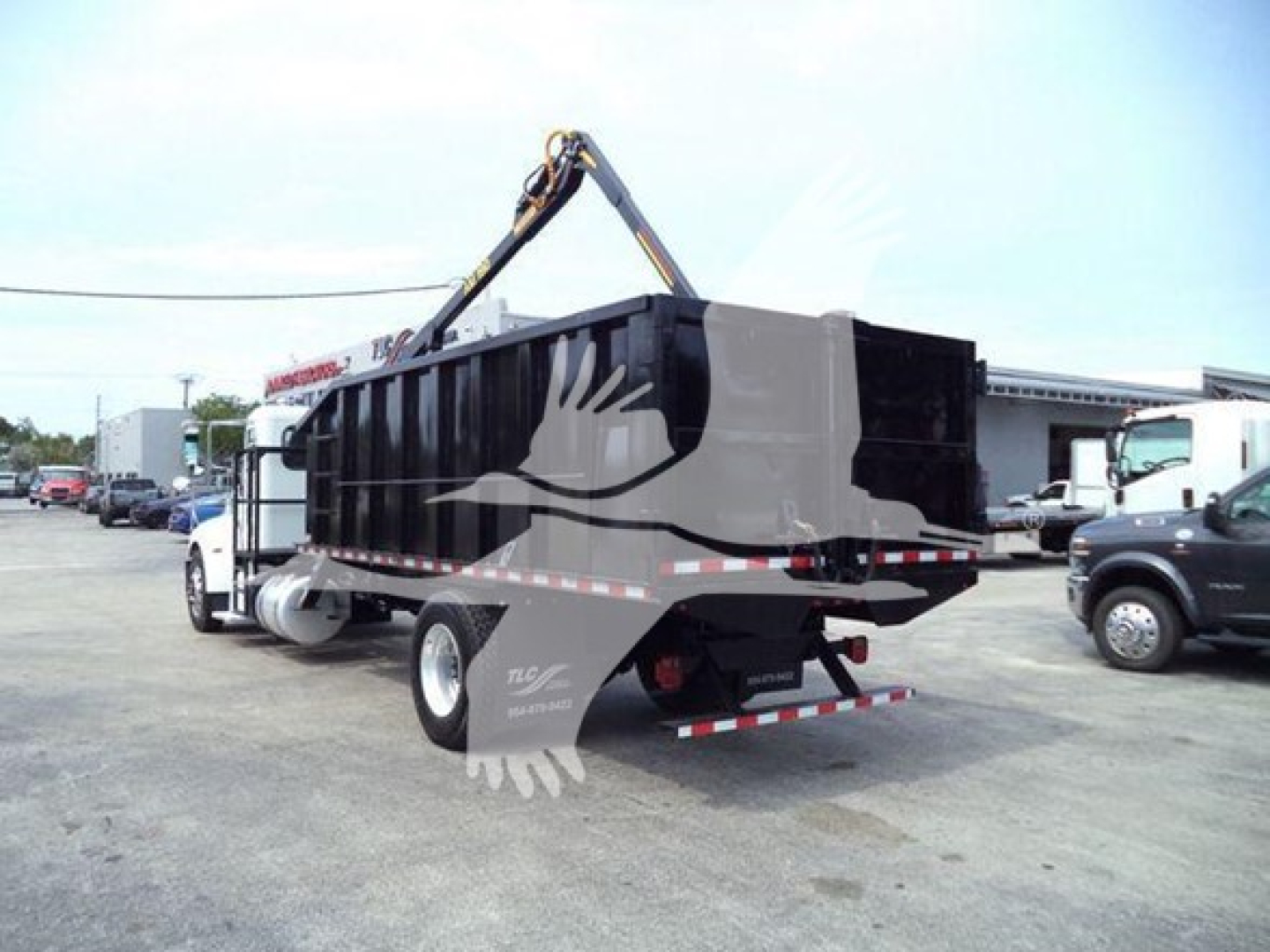 2020 Peterbilt 337 dump bed grapple truck rear view showing hydraulic crane and dump bed with stickers and rear underride undercarriage.