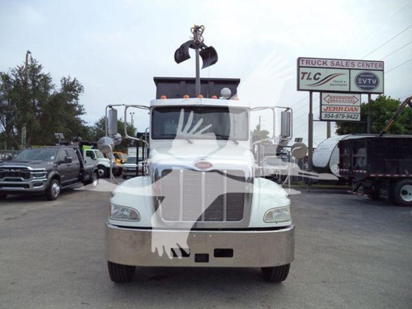 Front view of a white 2020 Peterbilt 337 grapple truck in a dealership lot, showing large chrome bumper, grille, headlights, and crane grapple mount above cab.