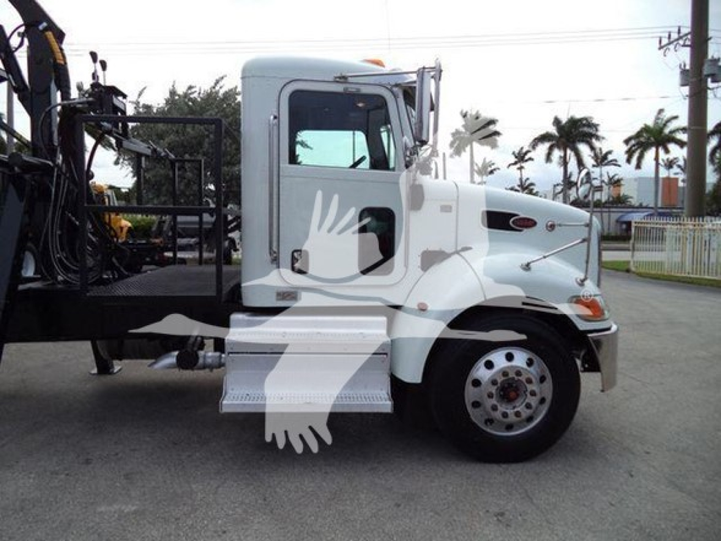 Truck side view showing white Peterbilt 337 grapple truck with branding and side steps.