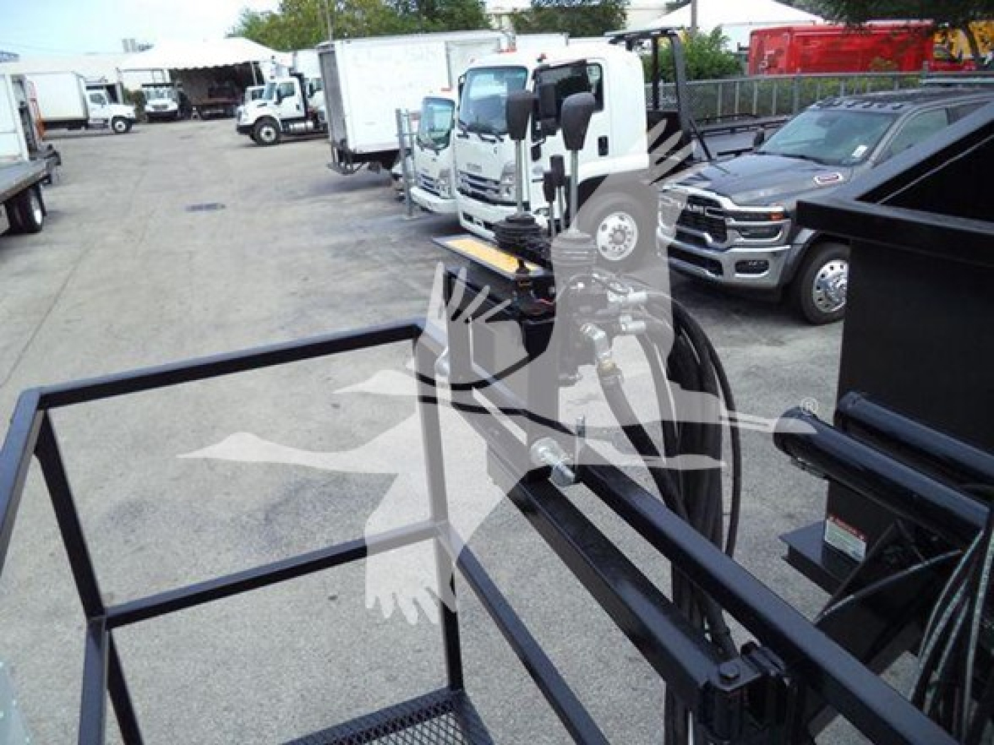 Peterbilt 337 grapple truck in a used inventory lot with a metal grapple frame in foreground and other trucks in background.