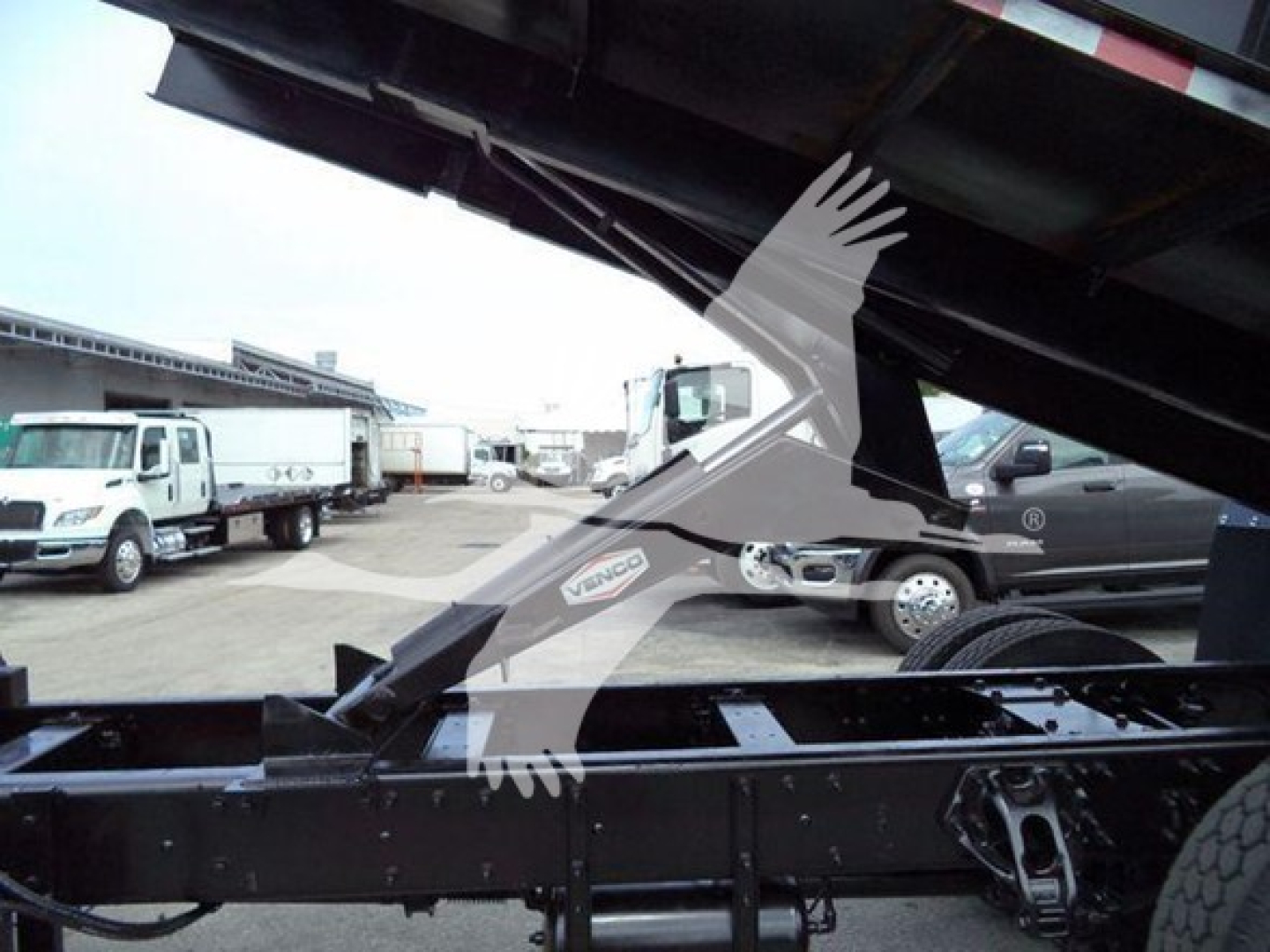 Peterbilt 337 grapple truck chassis frame and hydraulic arm partially raised, visible VIN plate area, truck yard in background.