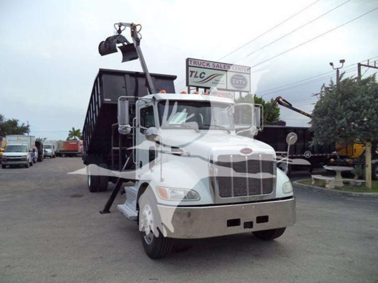 Peterbilt 337 grapple truck, front view with lift arm raised, white cab, chrome bumper, side mirrors, and grapple attachment in dump bed.