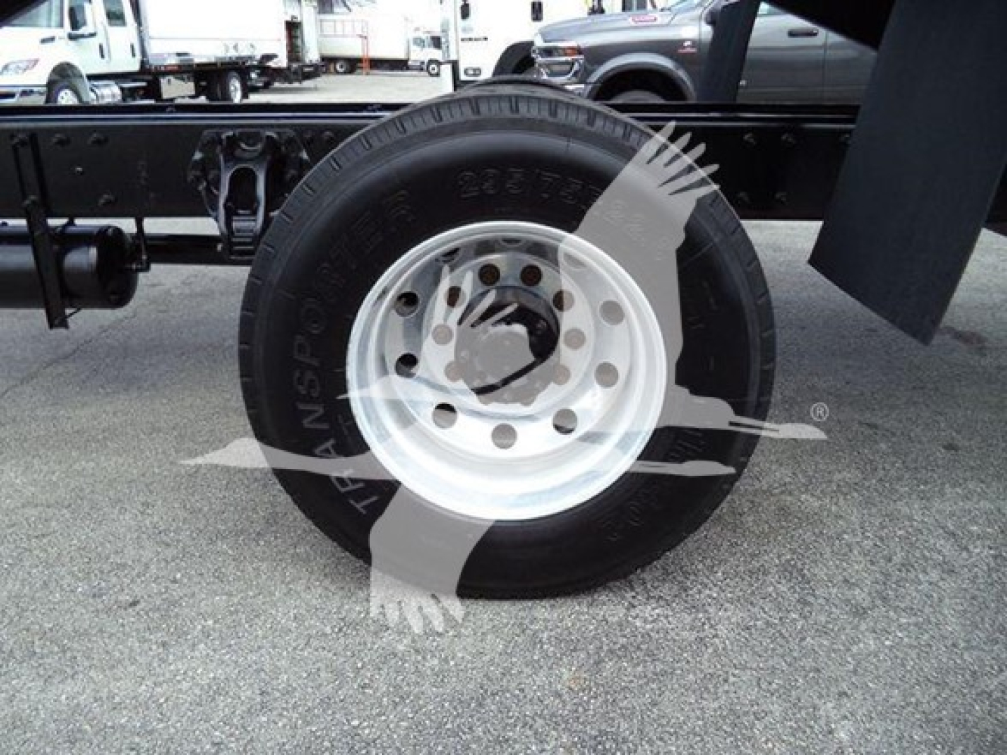 Peterbilt 337 wheel and front chassis area showing white wheel rim and black tire with visible bolt holes; background includes other trucks.