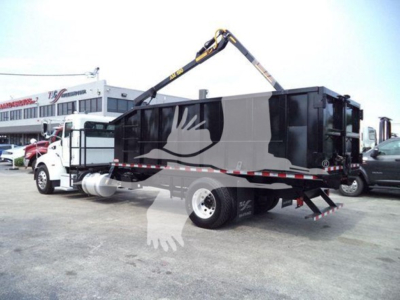 Peterbilt 337 grapple truck in service with hydraulic crane arm extended over a black dump body.