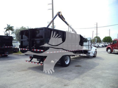 Peterbilt 337 dump truck with grapple attachment in driveway, side rear bunk, black container, white cab, crane arm overhead, stock number T18986.