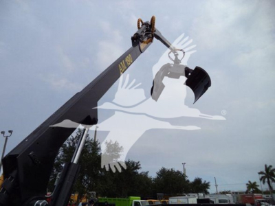 View of a 2020 Peterbilt grapple truck arm with a front loader/claw gripping a bucket against a blue sky.