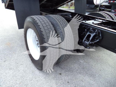 Peterbilt 337 chassis with dual rear tires and suspension, close-up of rear wheel area and axles showing two tires mounted on white rims under a grapple truck.
