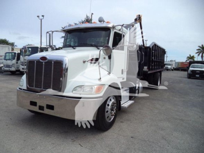 Peterbilt 337 truck in service showing front grille, cab, and grapple bed equipped with black dump container.