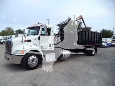 Truck engine bay side view showing white Peterbilt 337 grapple truck with black dump bed and crane.