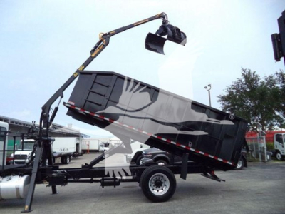 Truck with grapple sawsteel dump bed tilted up on a trailer. Visible text on the truck parts includes no legible model numbers in the image; overall shows a Peterbilt style grapple truck setup.