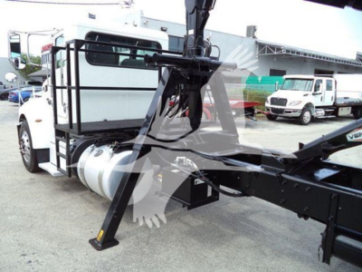 Peterbilt 337 truck chassis with grapple arm attachment and auxiliary lifting mechanism, side view showing cab, fuel tank, and framework.