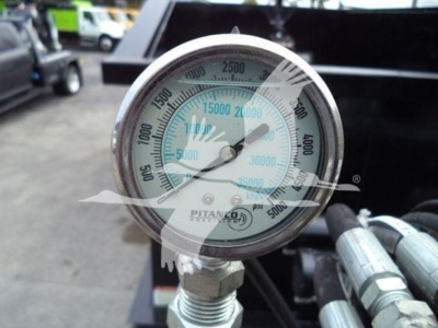 Gauged pressure dial on Peterbilt 337 grapple truck showing PSI/bar scales and tubing connections.