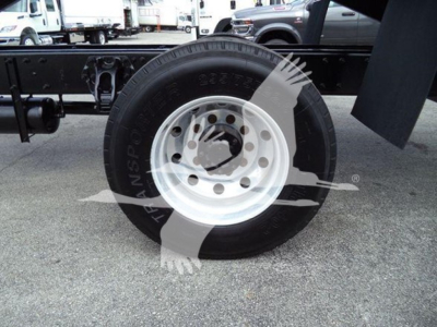 Peterbilt 337 wheel and front chassis area showing white wheel rim and black tire with visible bolt holes; background includes other trucks.