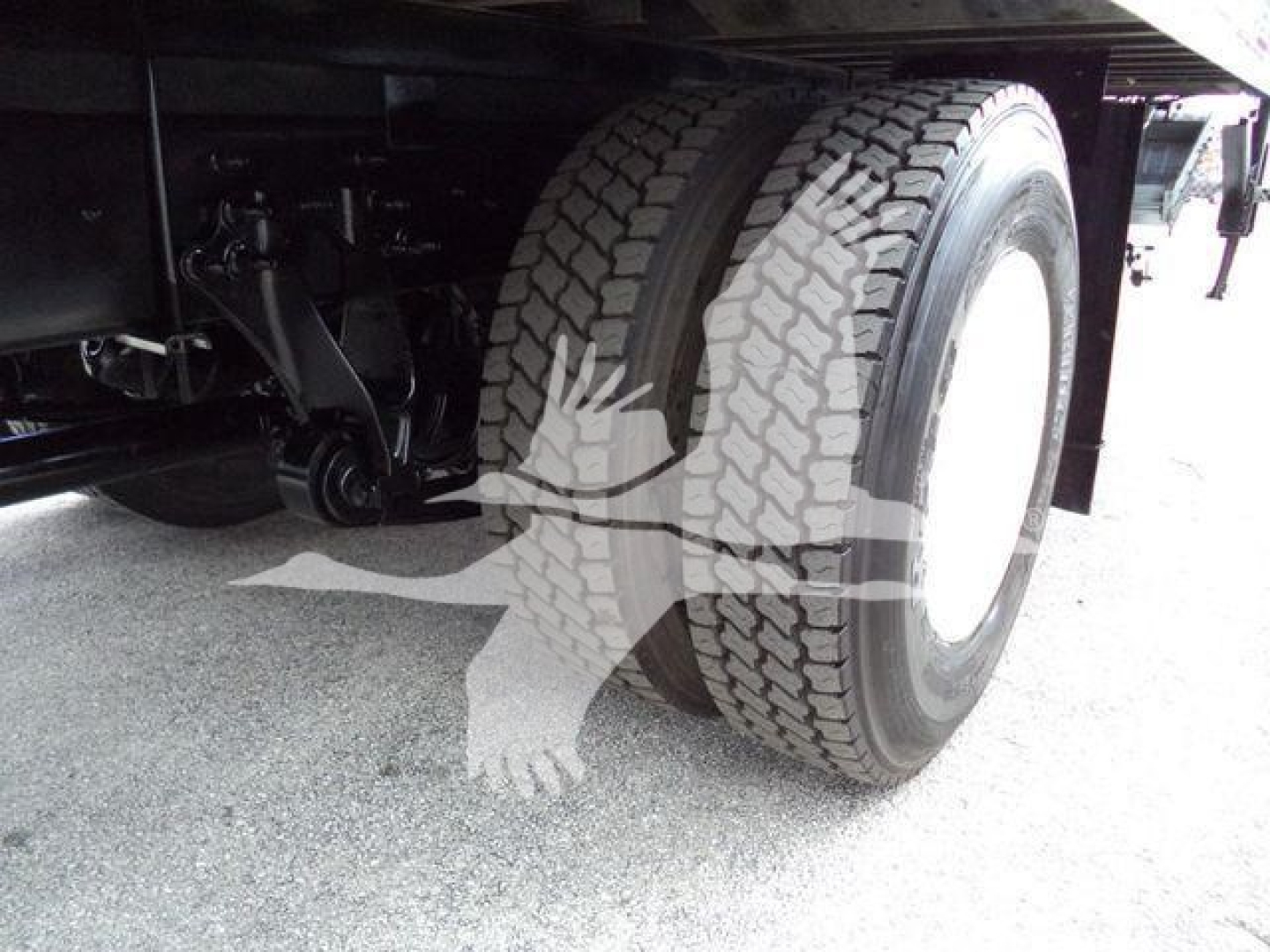 Dual rear wheels and suspension under a box truck showing heavy-duty tires and axle components.