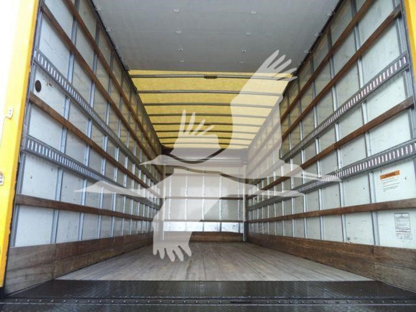 Empty cargo truck trailer interior with wooden floor and metal side rails; yellow exterior edges; faint watermark across image.
