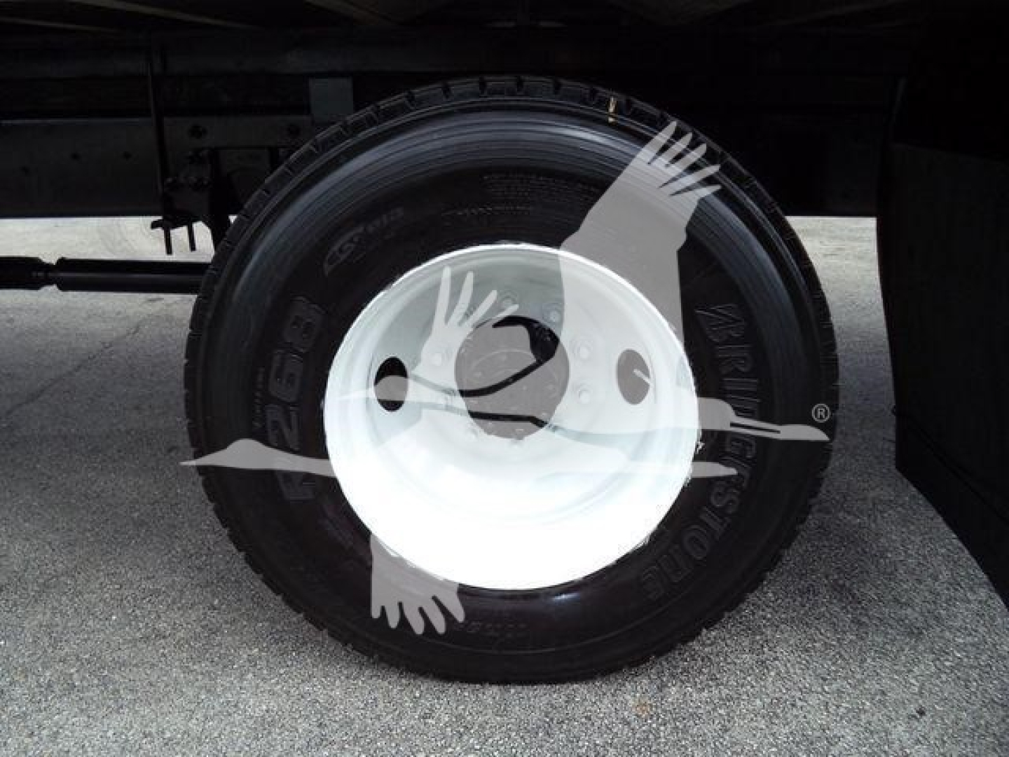 Wheel and tire view under a box truck showing a white steel rim and tire.