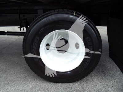 Wheel and tire view under a box truck showing a white steel rim and tire.