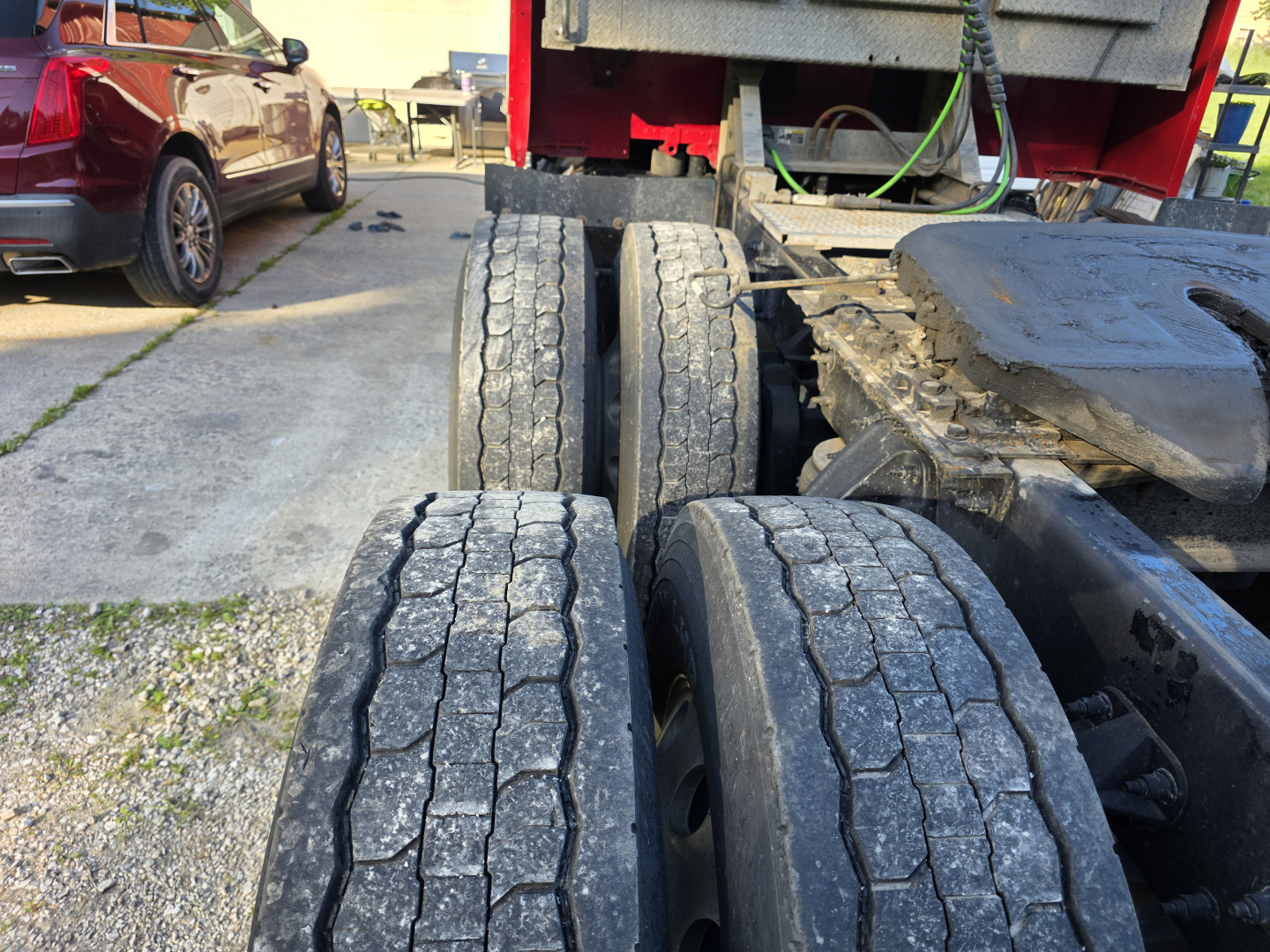 Peterbilt 579 truck chassis with three rear axles visible; wear on tire tread and road grime on components.