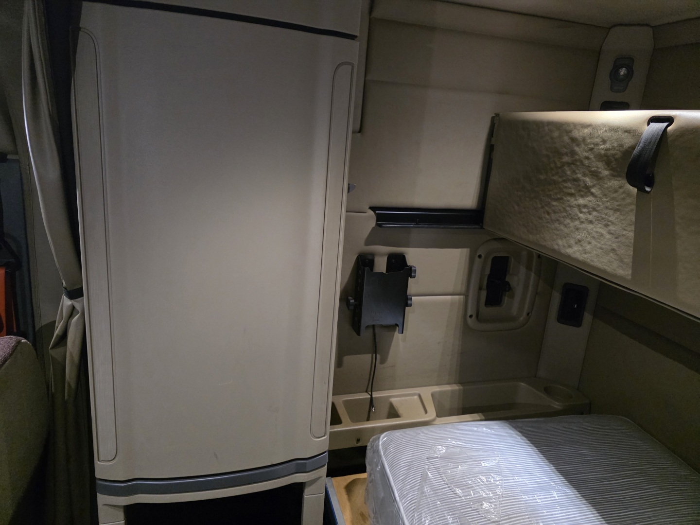 Cab interior of a Peterbilt 579 sleeper showing storage compartments and a bed mattress.
