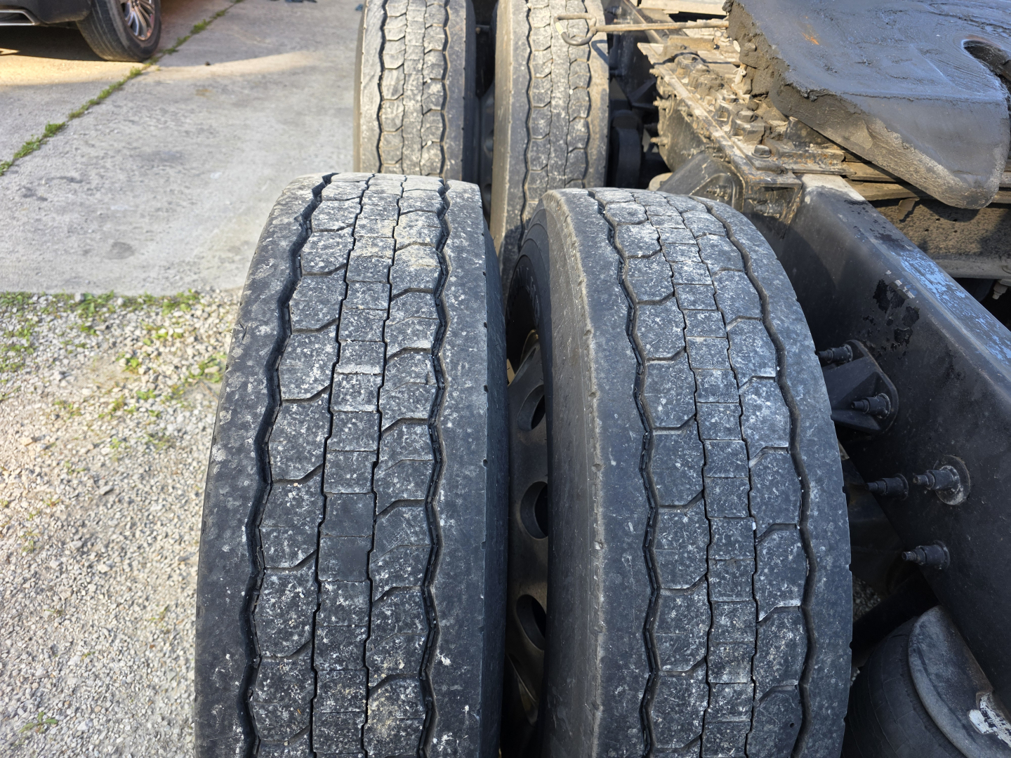 Trailer wheels and dual rear axles of a Peterbilt truck showing tread wear and mud/dust on tires.