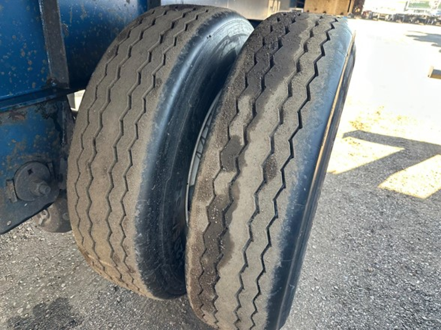 Great Dane flatbed trailer dual tires with tread visible, on a blue trailer chassis.