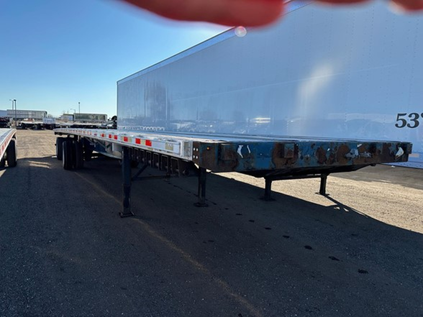 Flatbed trailer in-service showing lower frame with support legs and tandem axle undercarriage of a 2014 Great Dane Freedom Lt.