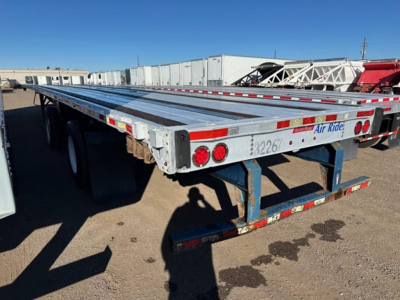 Flatbed trailer showing aluminum deck with red/white reflective tape and taillights, Great Dane logo and model number on side.