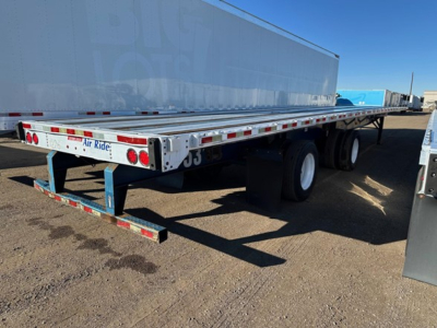 Flatbed trailer showing rear and side with reflective tape and bumper, undercarriage with dual wheels.