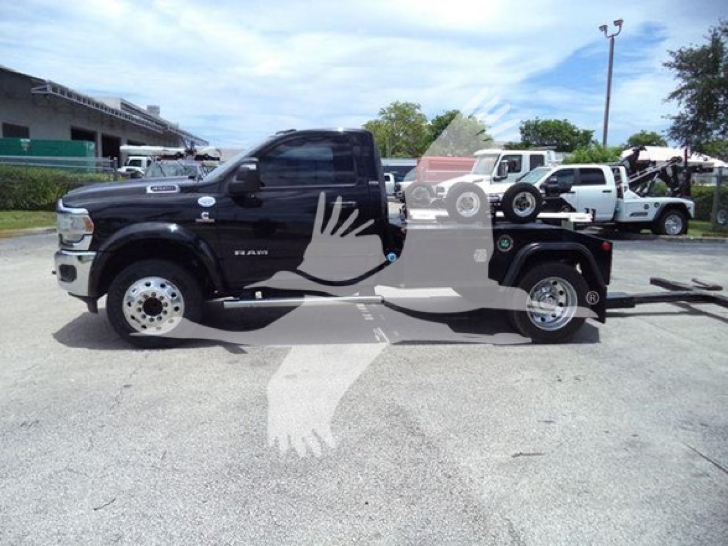 Ram 4500 tow truck side view showing winch category, black cab, white wheels, and long flatbed with equipment. Visible text includes RAM 4500 badge on door and the image shows a tow setup.